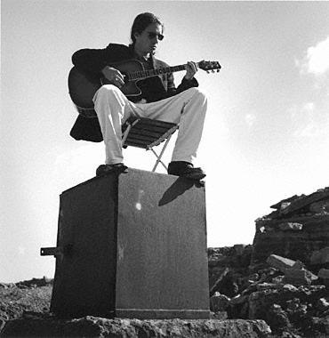 Calle playing guitar on top of rusty safe